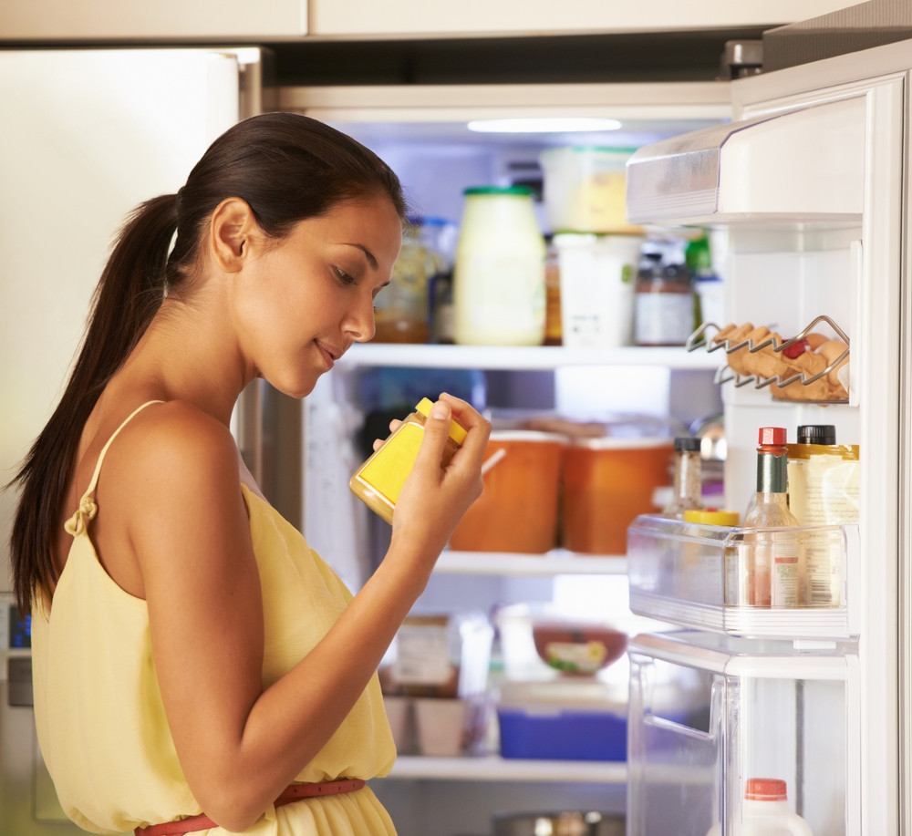 femme regarde aliments dans son frigo