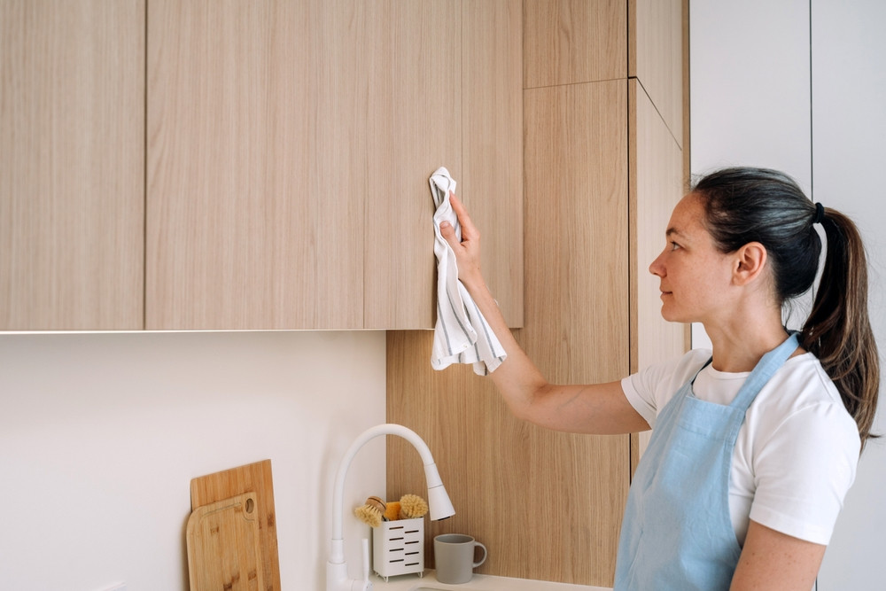 femme nettoie les placards de la cuisine
