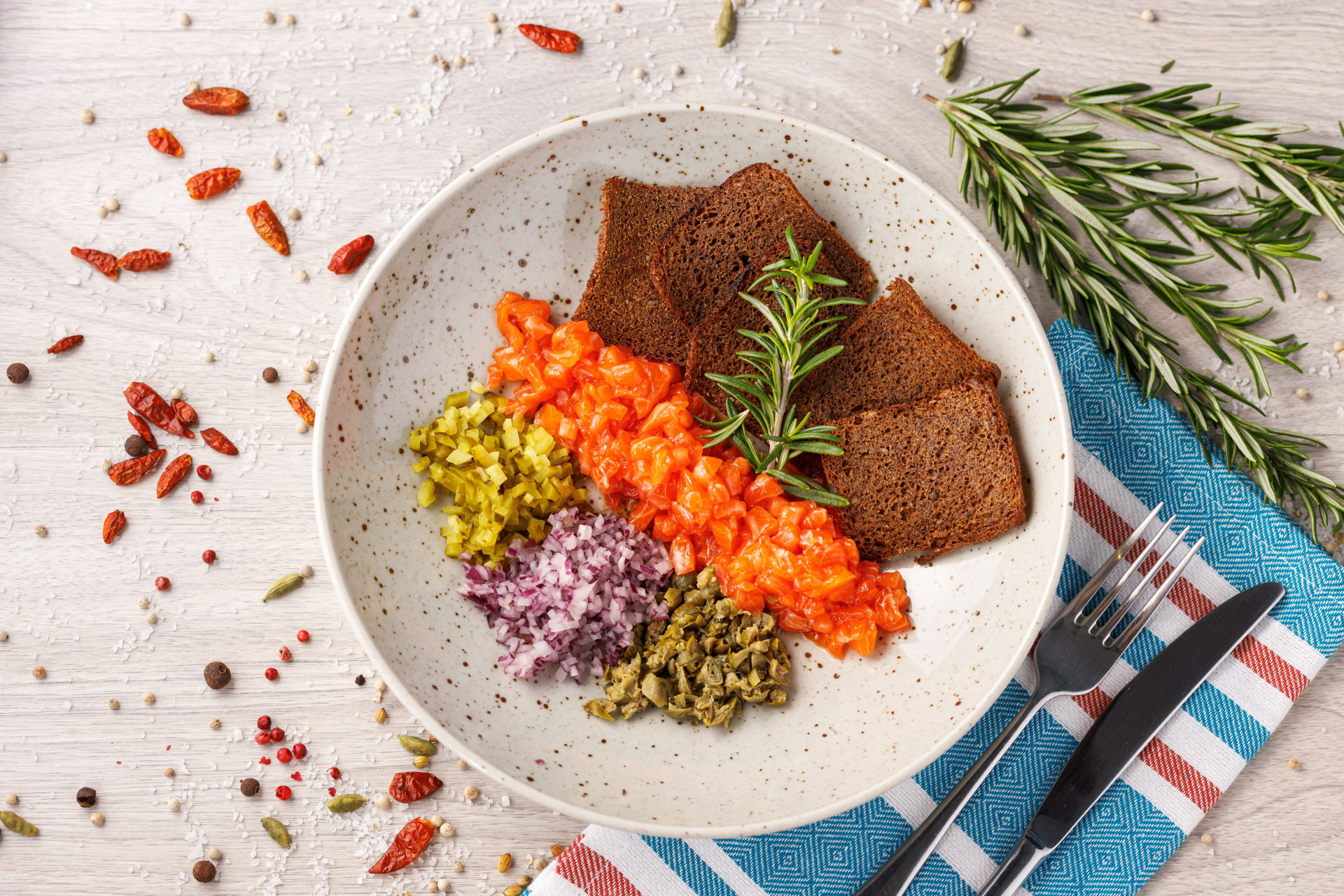 Vue de dessus d'un repas comprenant du pain brun, des légumes hachés et des épices sur une assiette.