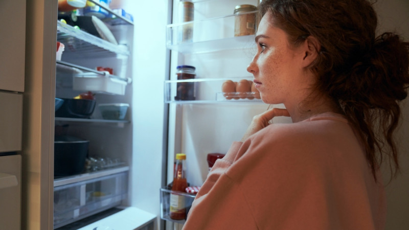 femme triste qui regarde dans son frigo