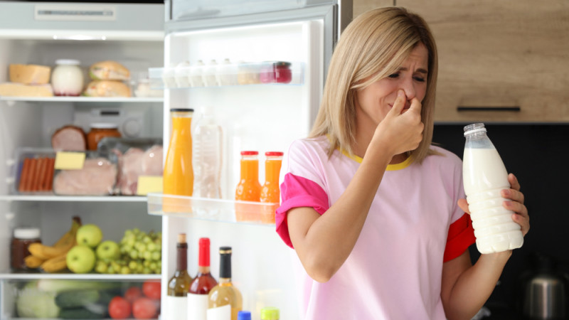 femme qui sent une bouteille de lait qui a tourné