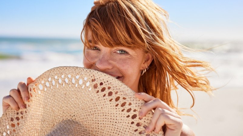 femme avec des cheveux roux sur la plage