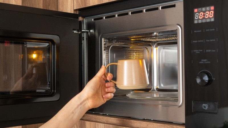 personne qui réchauffe sa boisson au micro-onde