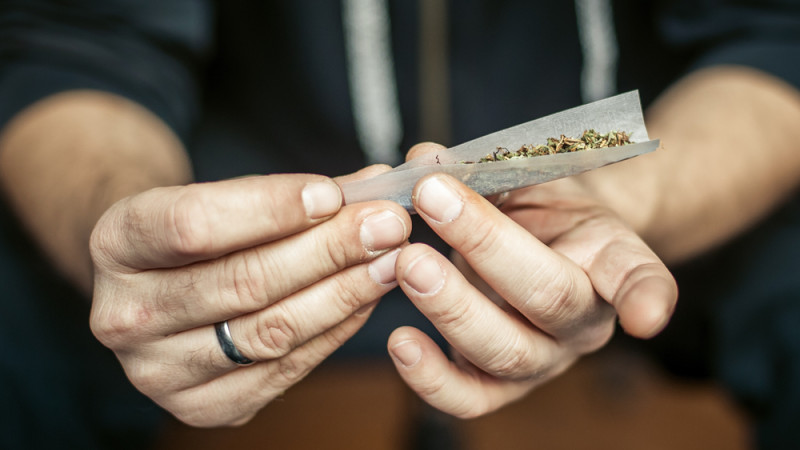homme qui roule un joint de cannabis