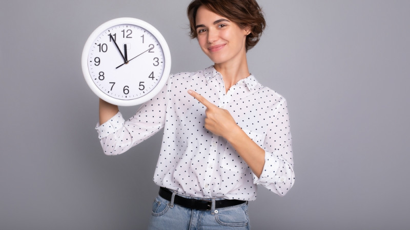 femme souriante tenant une horloge