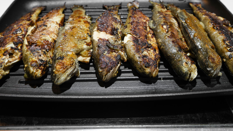 Gros plan de poisson grillé sur un plateau, mettant en valeur des textures délicieuses et croustillantes.