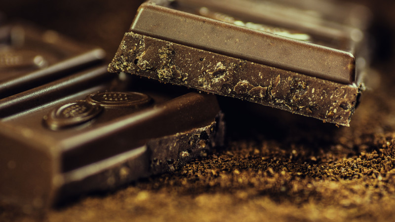 Gros plan de barres de chocolat noir riche saupoudrées de poudre de cacao, mettant en valeur la texture et l'indulgence.