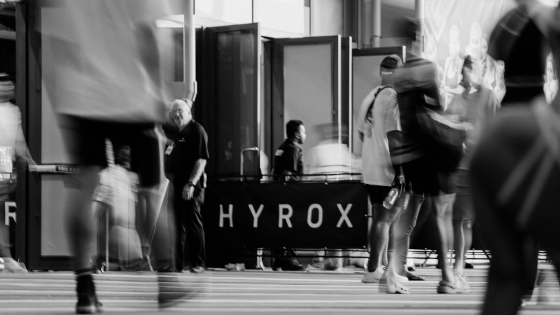 Motion-blurred people gather around a hyrox banner