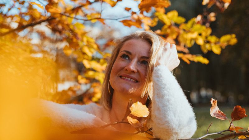 Une femme profitant du paysage automnal à Munich, en Bavière, entourée de feuilles dorées.