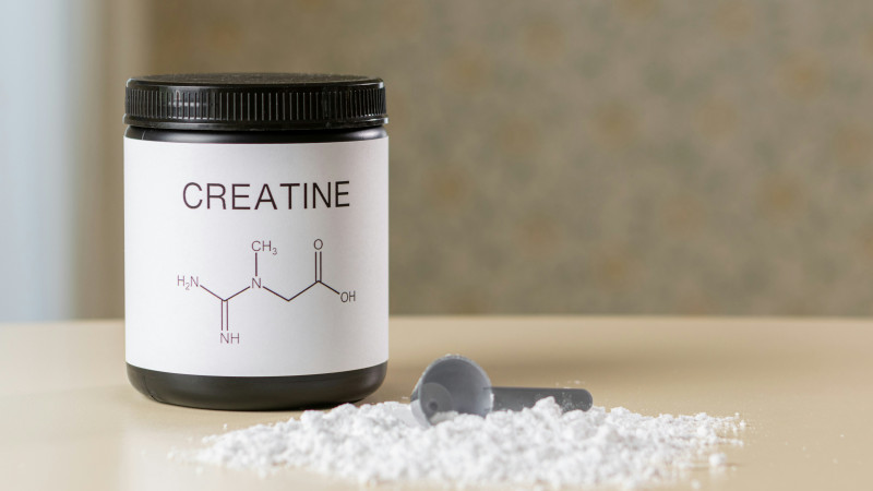 Creatine supplement jar and scoop with powder, muscle recovery and fitness