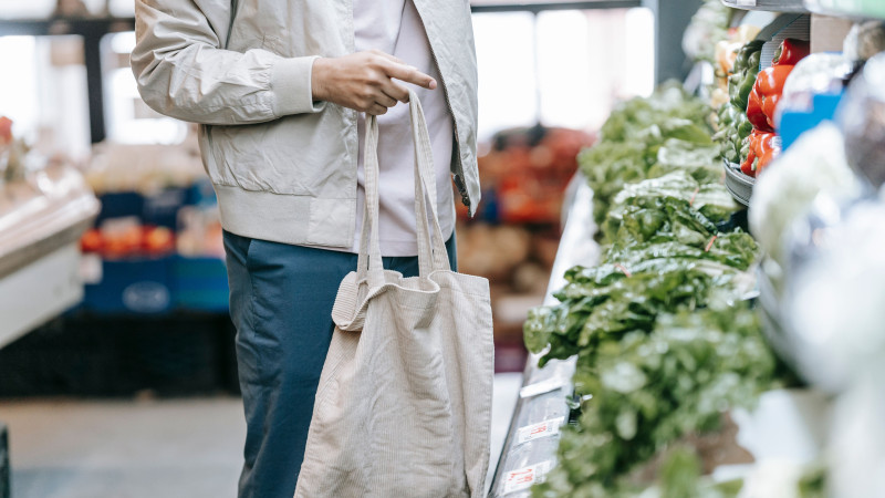 Homme choisissant des légumes frais dans une épicerie avec un sac écologique.
