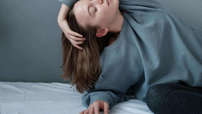 Une jeune femme en tenue douce reposant paisiblement à l'intérieur, dégageant une élégance calme.