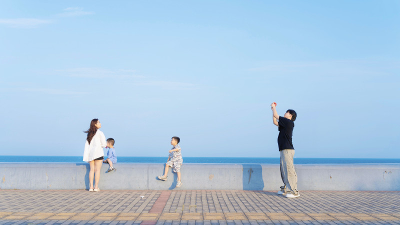 Une famille profitant d'une journée ensoleillée au bord de la mer avec un ciel bleu clair en arrière-plan.