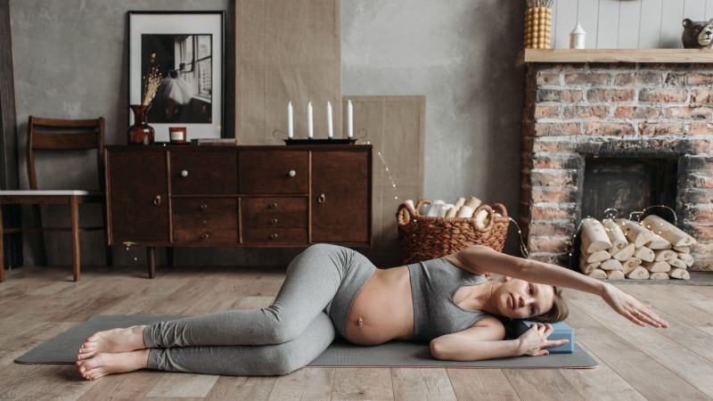 Une femme enceinte en tenue de sport pratiquant le yoga à l'intérieur pour un mode de vie sain.