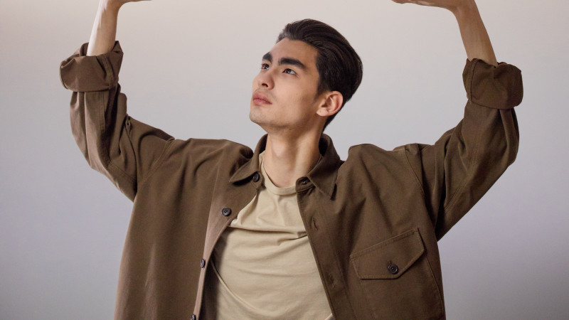 Un homme en manteau marron équilibre des boîtes étiquetées représentant divers défis de la vie comme le travail et l'argent.