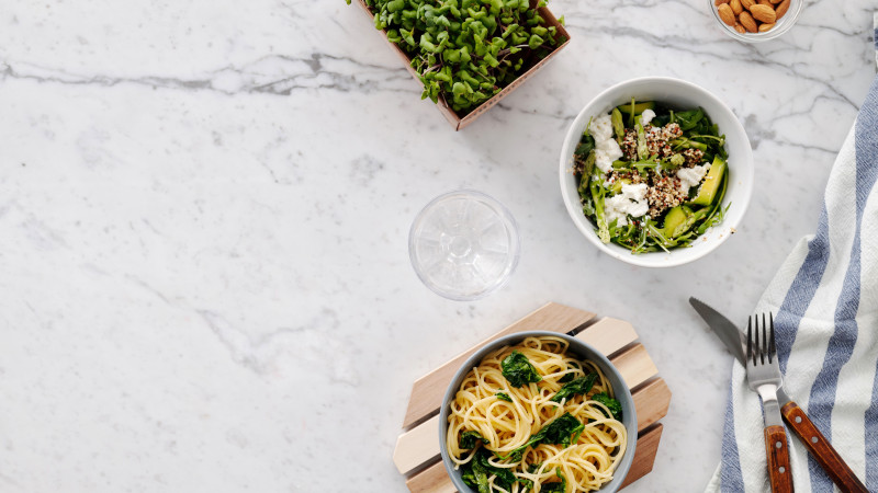 Vue de dessus d'un repas nutritif avec salade et pâtes sur une surface en marbre, parfait pour des thèmes de alimentation saine.