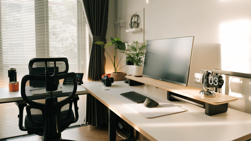 Bureau à domicile minimaliste avec chaise ergonomique, écran de bureau et plantes à la lumière naturelle du soleil.