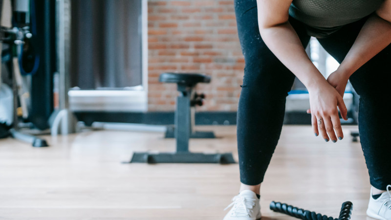 Une femme fait une pause dans son entraînement, se reposant à l'intérieur d'une salle de sport.