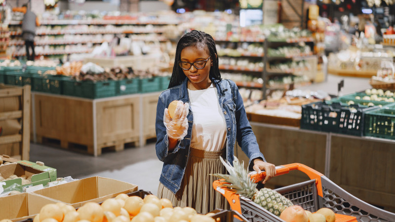 Une femme faisant des courses pour des produits frais dans un supermarché animé.