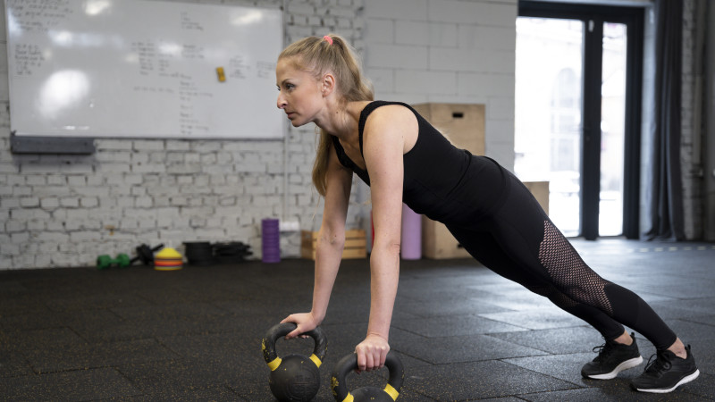 Personne dans la salle de sport à l'aide de kettlebells