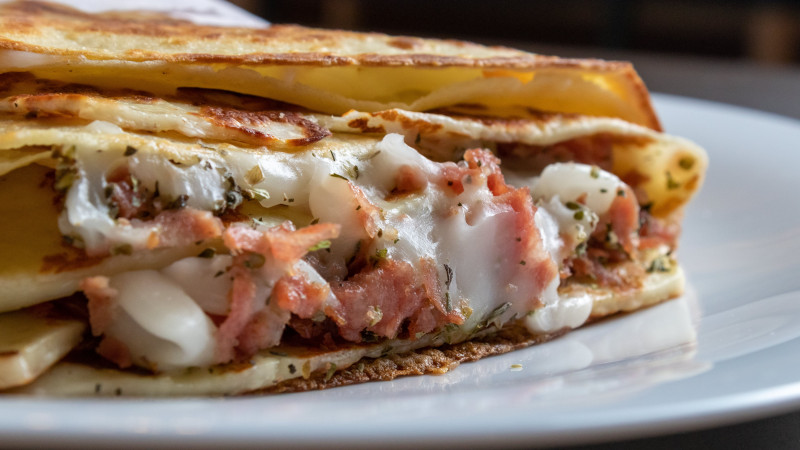 Gros plan délicieux d'une crêpe savoureuse remplie de fromage fondu et de jambon.