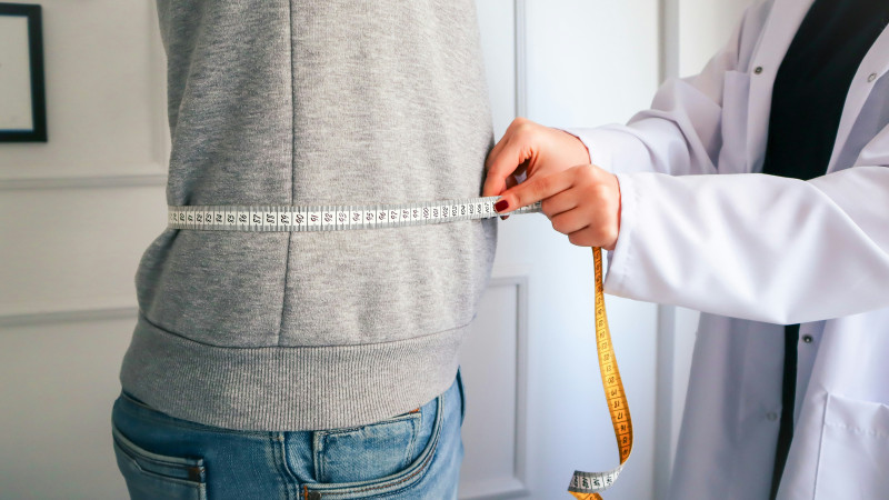 a woman measuring her waist with a measuring tape