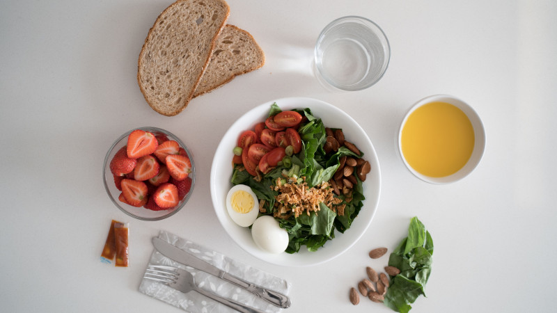 Vue de dessus d'un petit déjeuner nutritif avec salade, œufs, pain et jus, parfait pour un départ sain.
