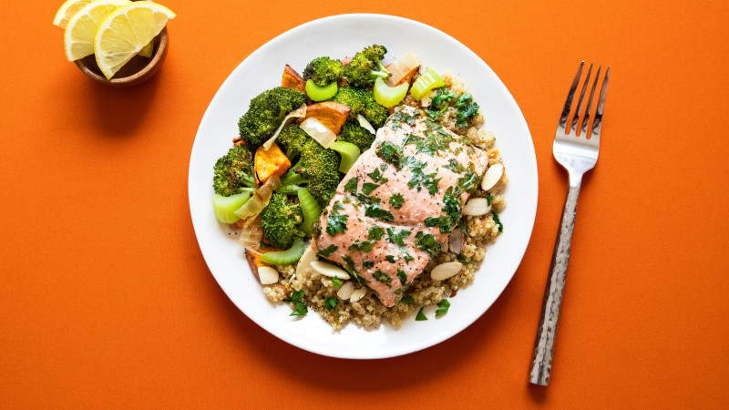Healthy salmon + veggies + quinoa dish I made for lunch on a orange background for contrast.