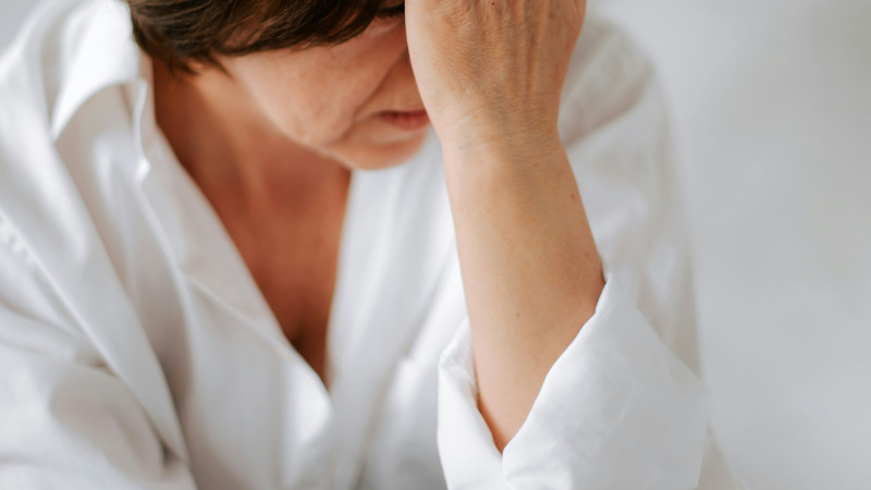 a woman sitting on a bed holding her head in her hands