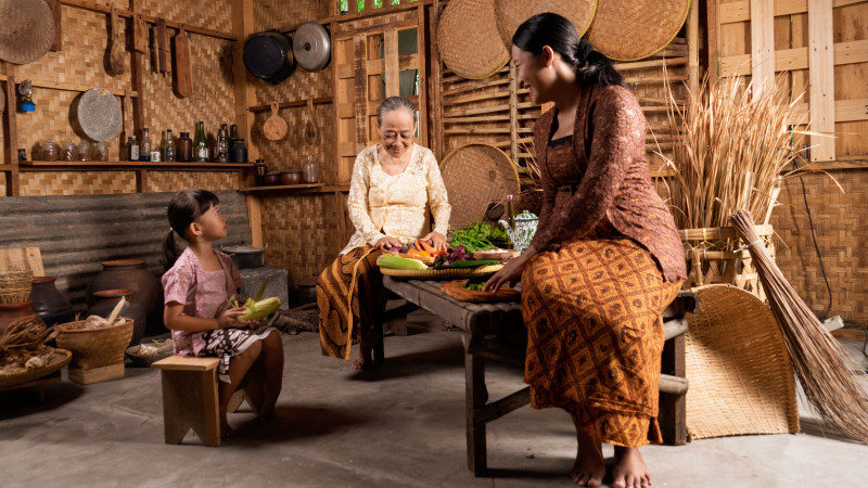 Trois générations cuisinant ensemble dans une cuisine traditionnelle en bambou.