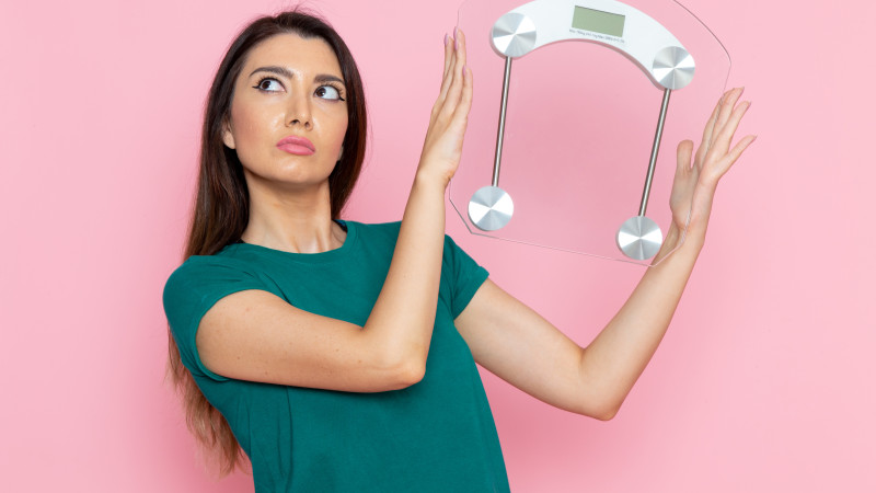 Vue de face jeune femme tenant des échelles sur le mur rose exercice sport entraînement athlète taille beauté