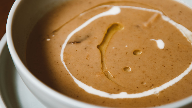 Gros plan d'une riche soupe aux champignons garnie d'un tourbillon crémeux et d'huile d'olive, parfaite pour les amateurs de cuisine gastronomique.