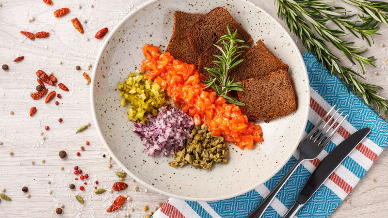 Vue de dessus d'un repas comprenant du pain brun, des légumes hachés et des épices sur une assiette.