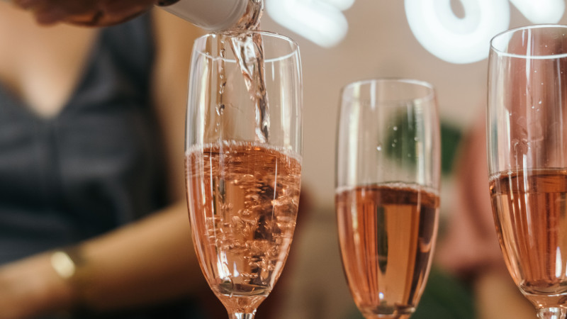 Gros plan de vin rosé versé dans des flûtes à champagne élégantes lors d'une célébration.