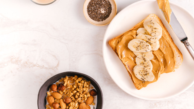 Plan rapproché d'un petit-déjeuner nutritif avec du pain à la banane, des graines de chia et des noix sur une surface en marbre.
