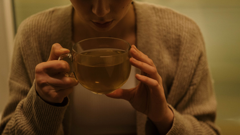 Une femme savoure une tasse de thé relaxante, créant une atmosphère chaleureuse et tranquille.
