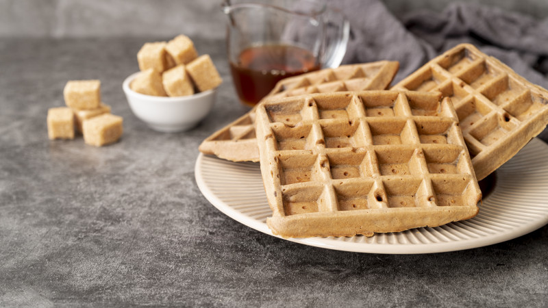 Angle élevé de gaufres sur une plaque avec des morceaux de sucre et du sirop