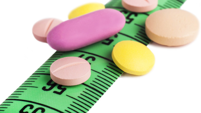 Gros plan sur les médicaments colorés sur le ruban à mesurer vert sur la surface blanche